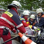 Die verletzte Person ist aus dem Fzg. gerettet und auf die Fahrtrage auf einer Vakuummatratze gelagert. Sie trägt einen Stiff-Neck zur Stabilisierung der Halswirbelsäule.