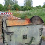 Ein mit Holz gefüllter Müllcontainer brennt lichterloh, aber die Feuerwehr ist gleich da.