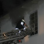 Ein Feuerwehrmann versucht sich einen Zugang über das Fenster zu verschaffen.